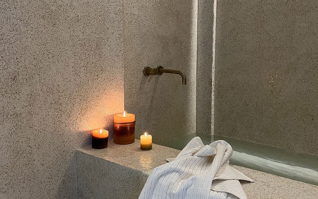 Terrazzo Granitech microtopping applied on bathroom walls showing seamless textured finish around bathtub with candles