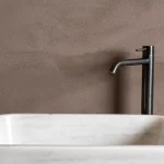 Terrazzo Granitech resin microtopping on bathroom wall in taupe finish with marble sink.